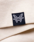 Black Benchmade Butterfly Logo Patch - Close-Up Detail on Cream Hoodie | Benchmade Knife Co.