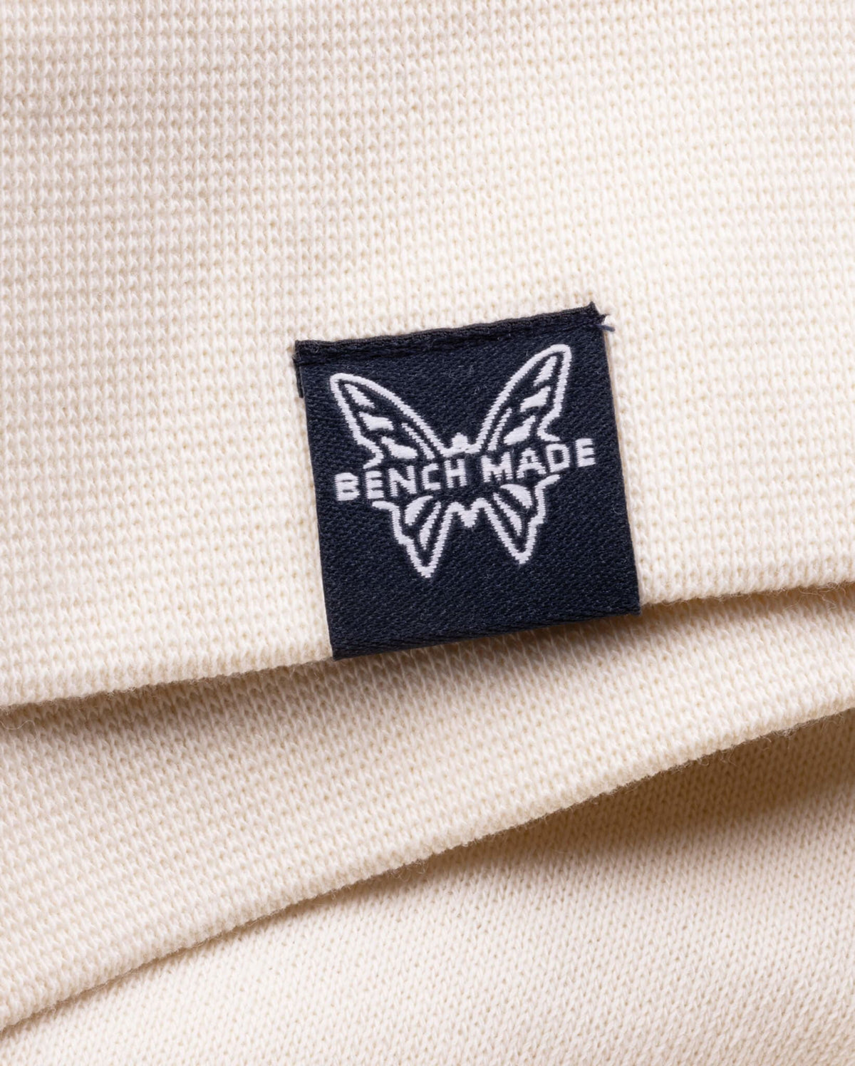 Black Benchmade Butterfly Logo Patch - Close-Up Detail on Cream Hoodie | Benchmade Knife Co.