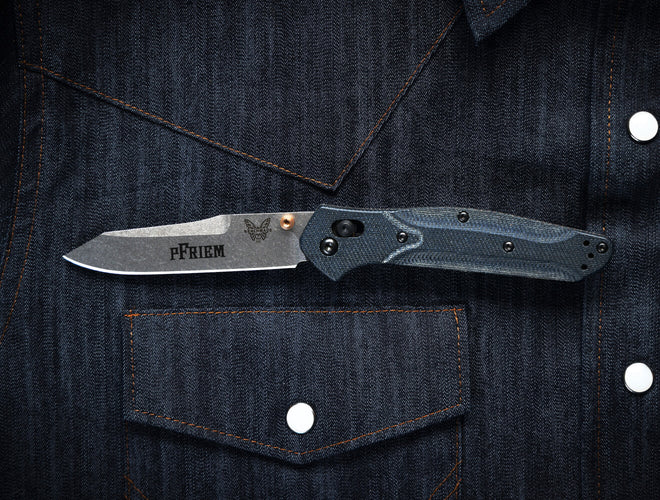 Custom Benchmade Bugout with a company logo laser-marked on the blade, shown on durable workwear as a branded employee gift.